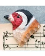 Houten koelkastmagneet Putter van Wildlife Garden met rode gezichtstekening, zwart-witte kop en bruine vleugel, gefotografeerd op bladmuziek.