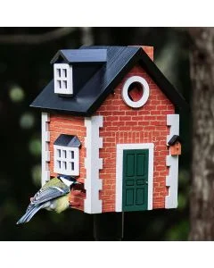 Koolmees bij de voederopening van de Multiholk Brick Cottage van Wildlife Garden, een houten nestkast en voederhuis met rode baksteenlook, groene deur en zwart dak.