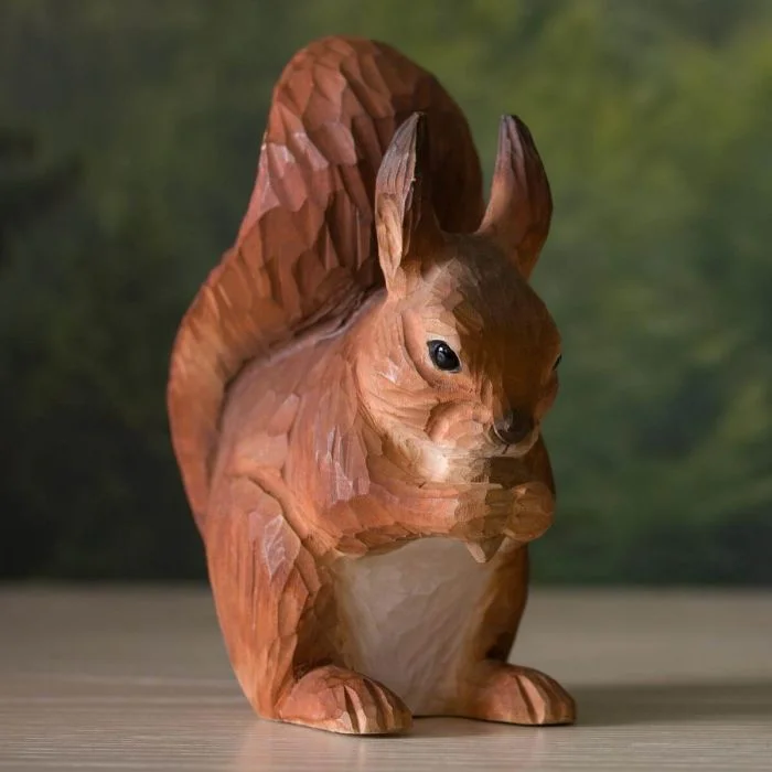 DecoAnimal Rode Eekhoorn van Wildlife Garden op een houten ondergrond, met roodbruine vacht, witte buik, rechtopstaande oren en grote pluimstaart.