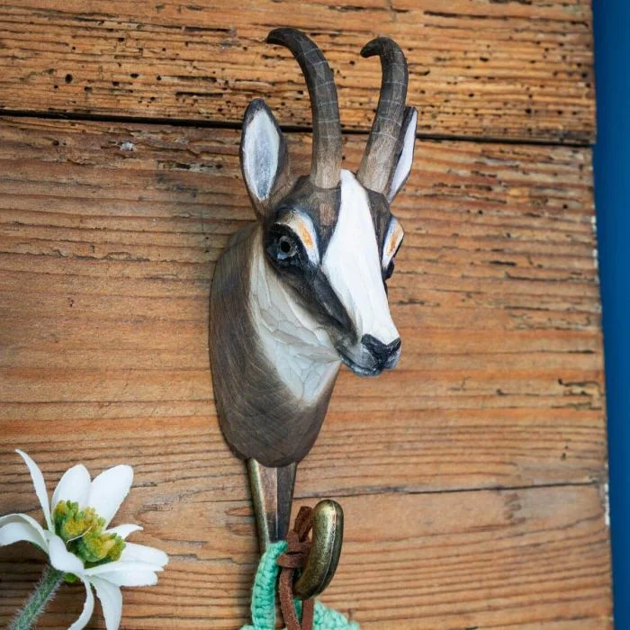 Kledinghaak Gems van Wildlife Garden aan een houten wand, met twee naar achteren gebogen hoorns, witbruine kop en messingkleurige metalen haak.
