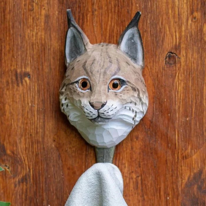 Kledinghaak Lynx van Wildlife Garden aan een houten wand, met een bruin-witte lynxkop en een handdoek aan de metalen haak.